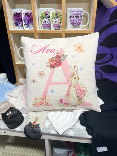 A pink capital letter A printed on a linen nursery cushion